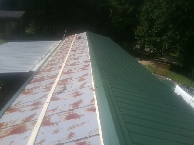 Old rusted panels beside newly installed green metal roofing — Wind Damage Roof Repair by Roofing Brothers in Kelso