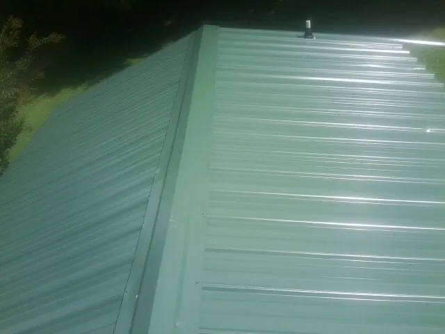 New green metal panels meeting at the ridge of a roof — Flat Roof Repair work by our crew in Kelso