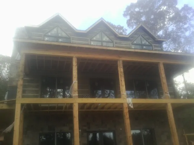 Dormers and porch framing on a large log home under construction — Roof Coating work by our crew in Kelso