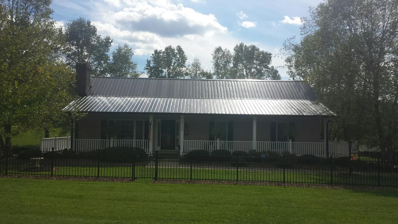 Gray metal roof on a brick ranch with a full width front porch — Gutter Guard Installation work by our crew in Kelso