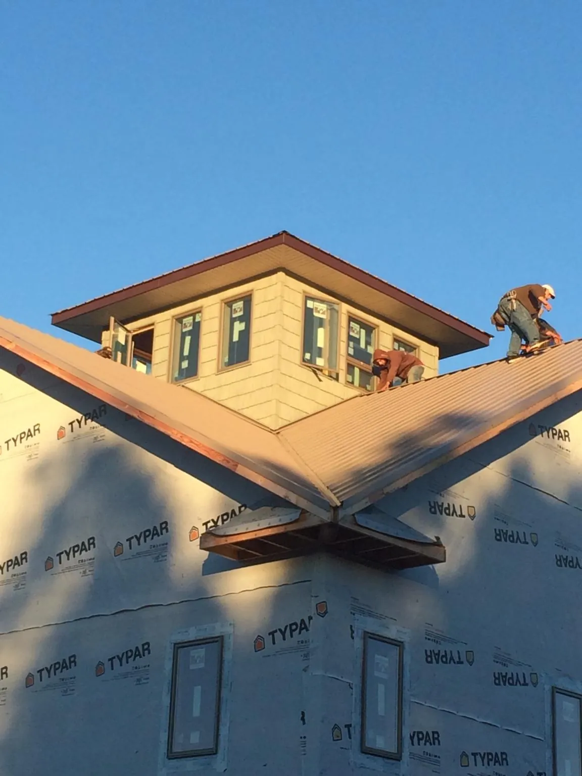 Roofers working around a rooftop cupola on a new metal roof at sunset — Roof Waterproofing in Kelso by Roofing Brothers